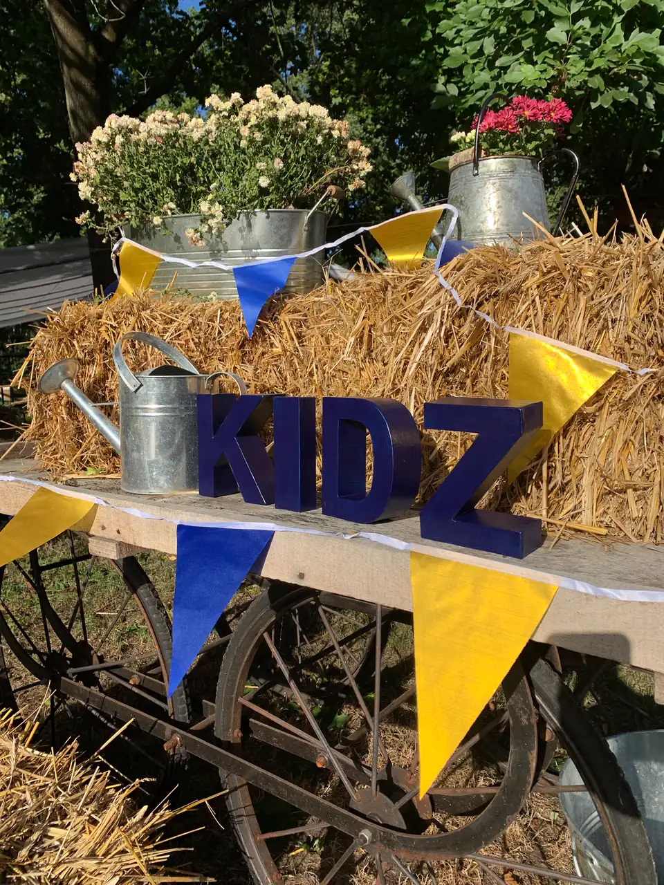 KIDZ-Schriftzug auf einem Heuwagen, geschmückt mit blauen und goldenen Wimpeln